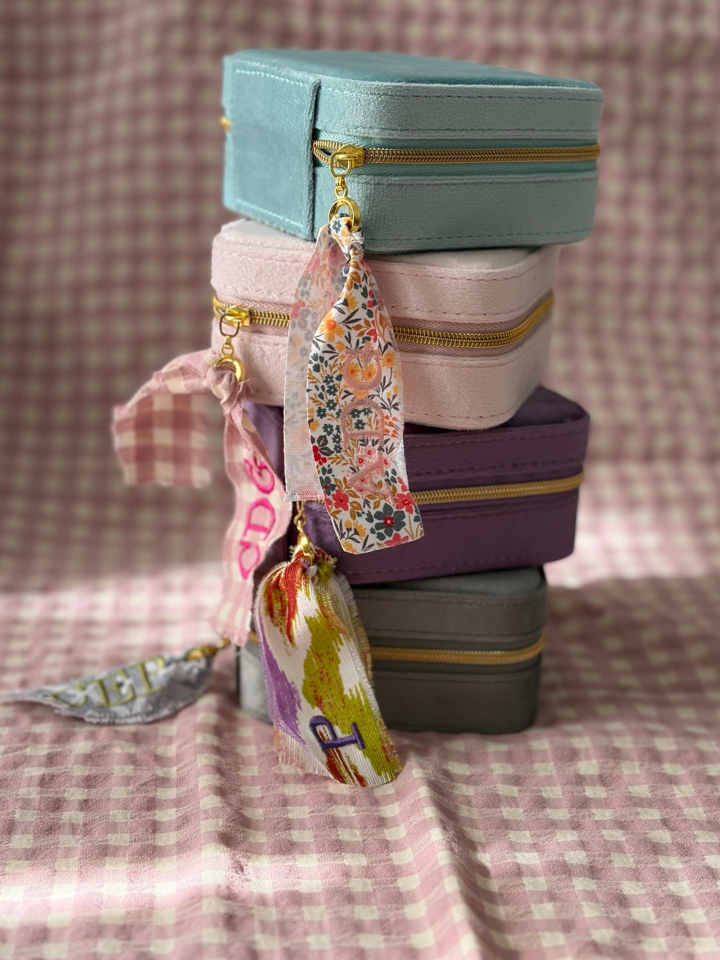 Joyero de viaje en terciopelo apilado en cuatro colores: menta, rosa, morado y gris, con cintas personalizadas